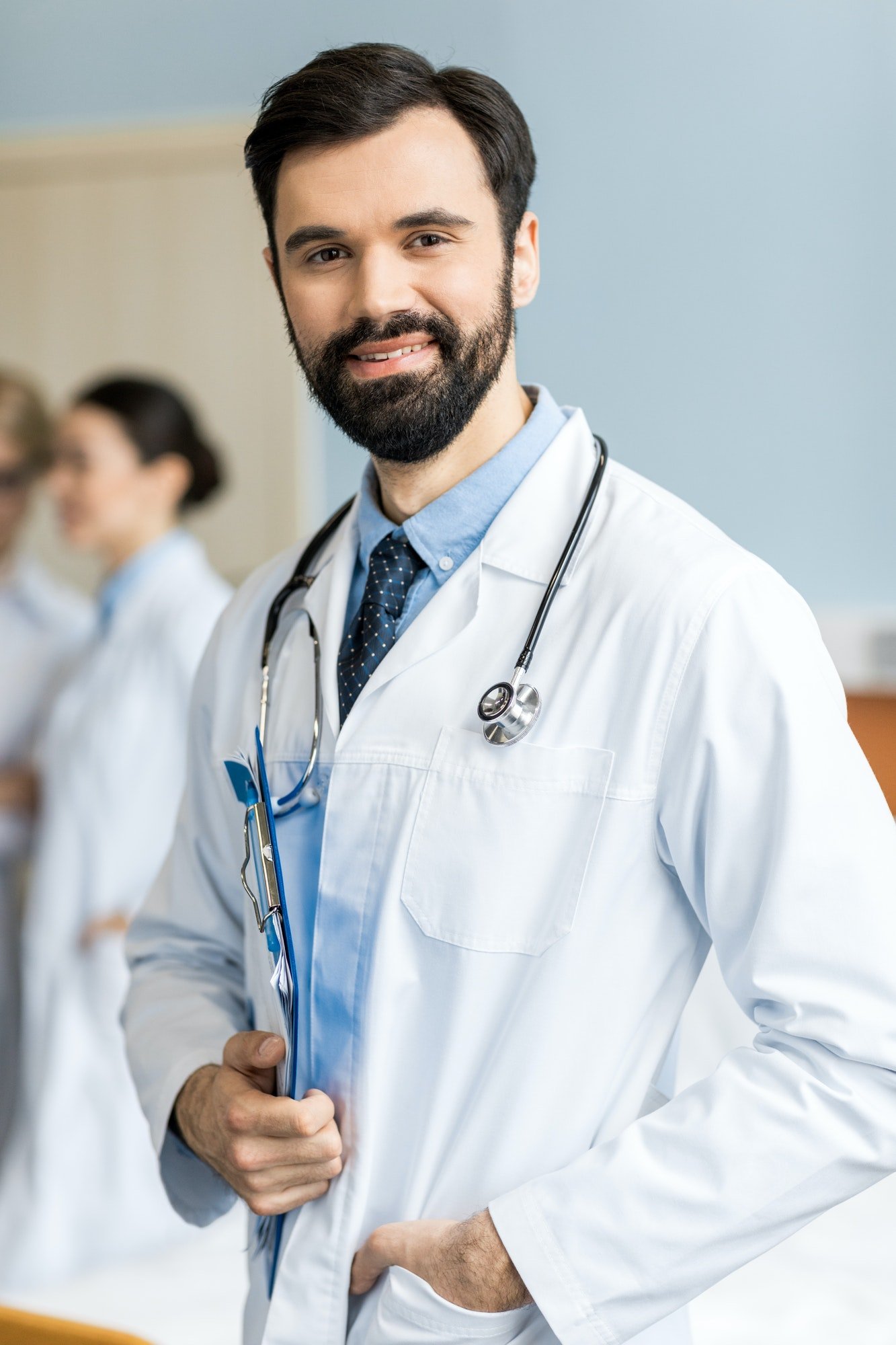 portrait-of-smiling-doctor-with-doctor-stethoscope-and-folder-in-clinic